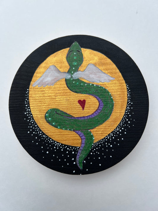 A circular painting of a green snake with a purple belly, white spots along its back, and small wings.  Behind it is a golden full moon on a black background with small white dots surrounding the bottom half of the moon.