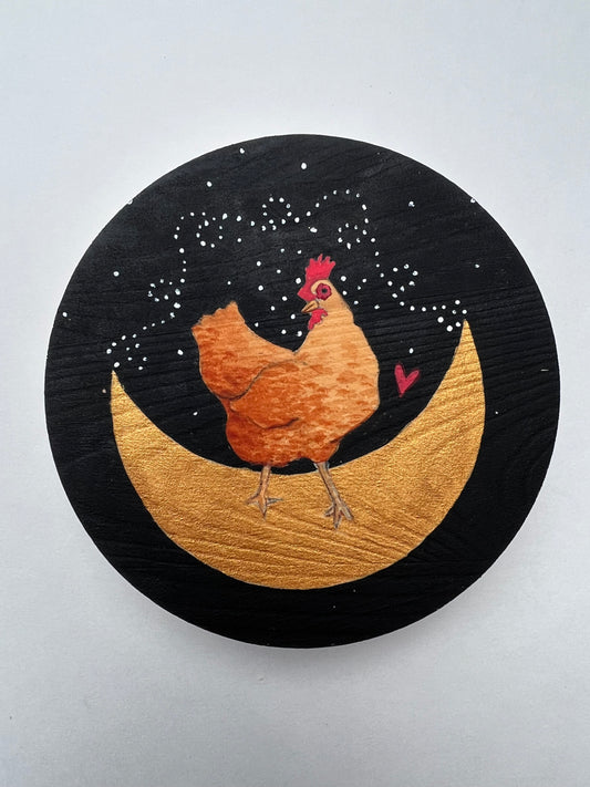 a painting of a brown chicken dancing on a golden crescent moon.  The background is black with a small red heart and white dots.